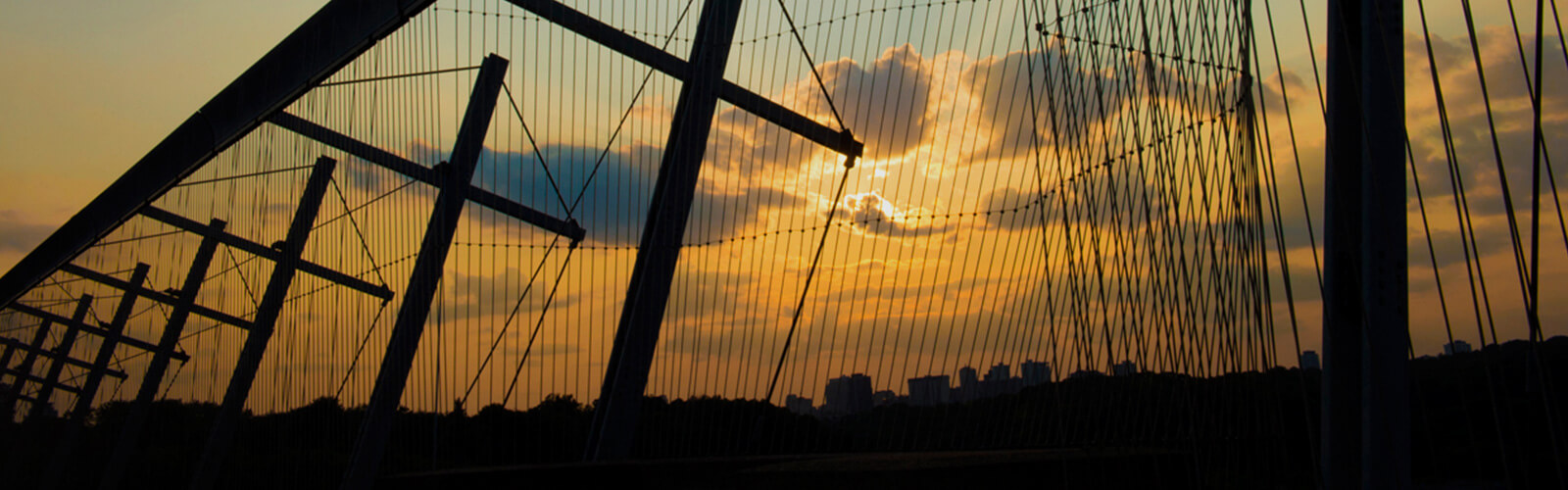 Silhouette of the Luminous Veil with a view of the valley and sunset beyond it.